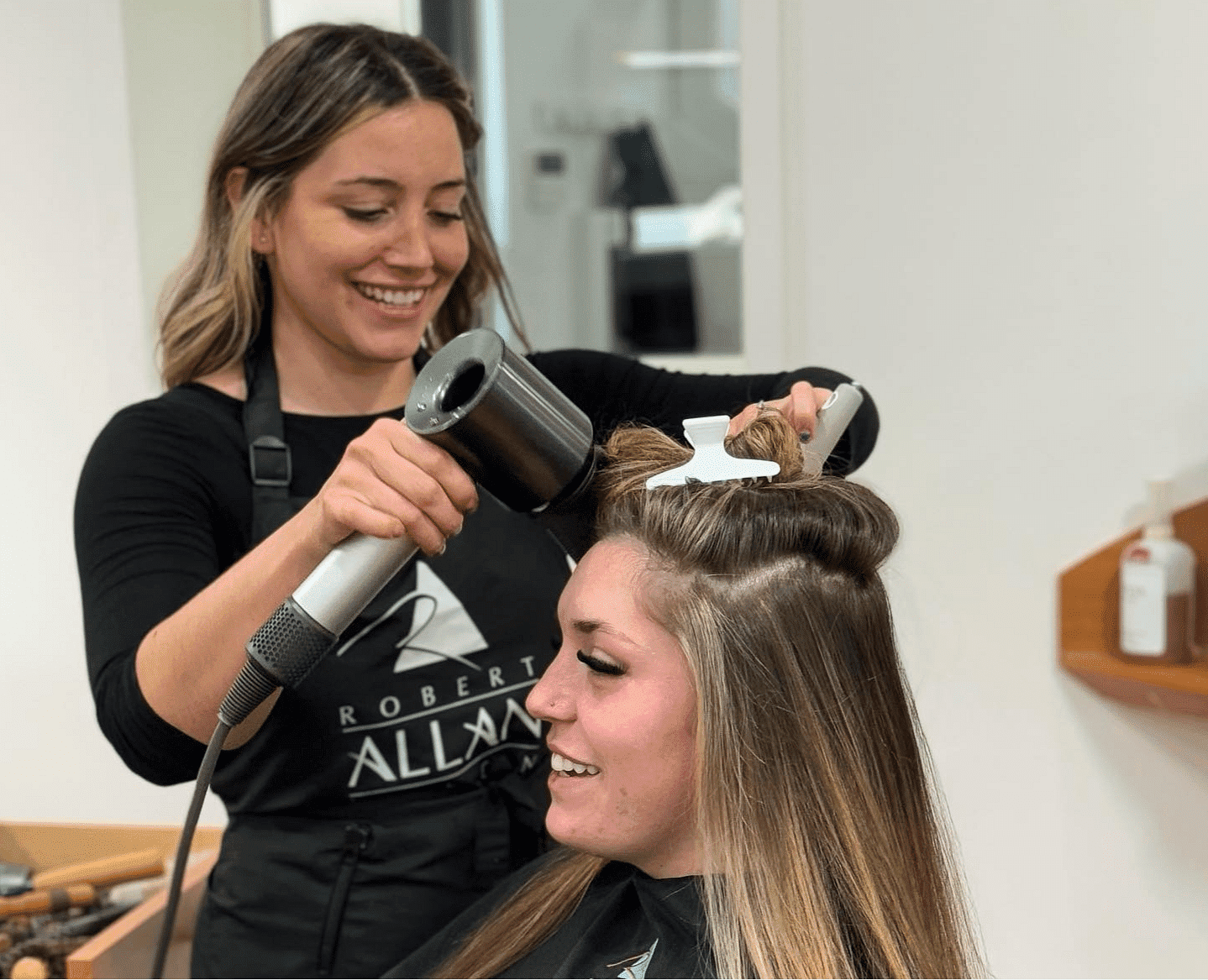 Hairstylist blow-drying a client's hair in a modern salon.